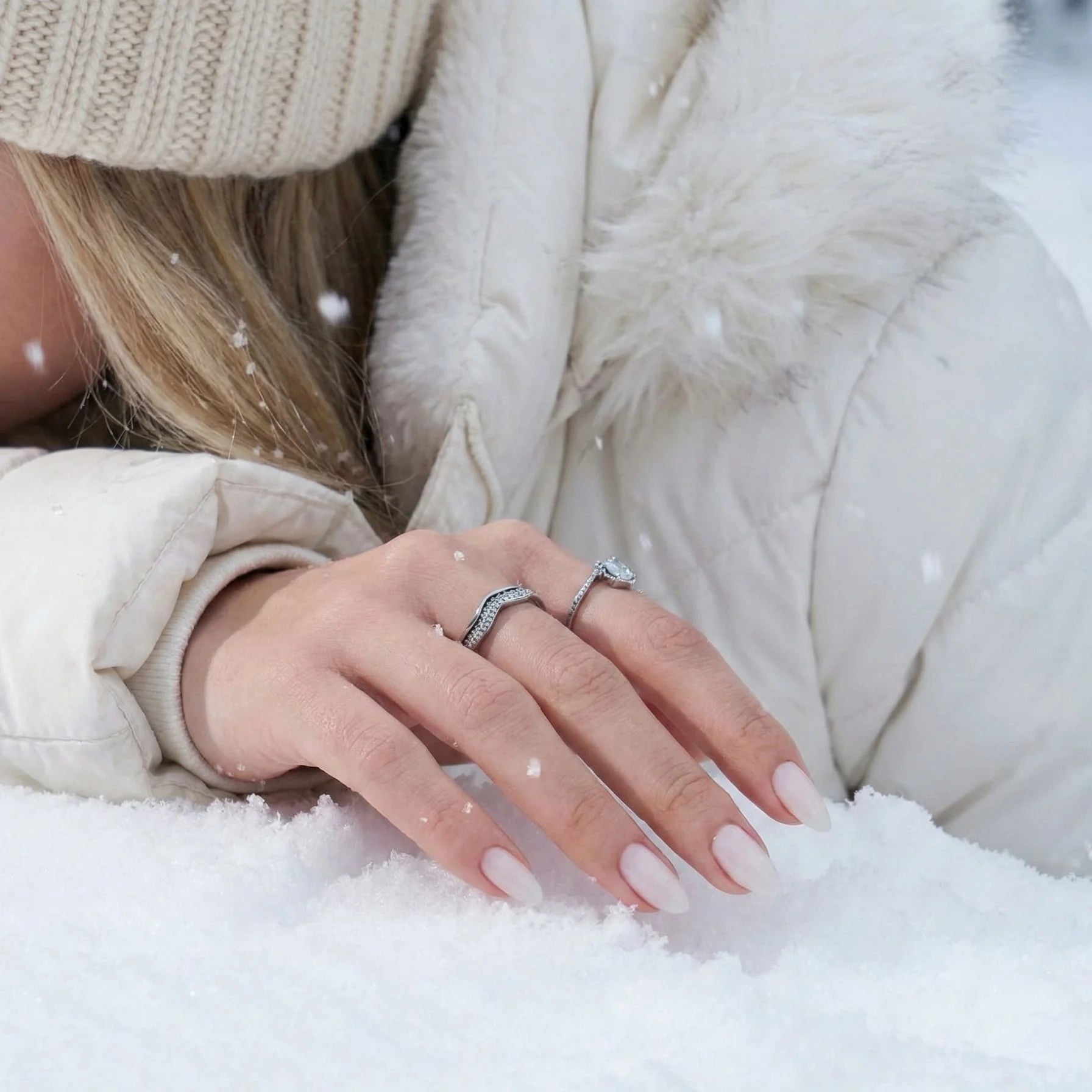 Satin Snow lösnaglar lifestyle – krämvita mandelnaglar i snölandskap med dunjacka