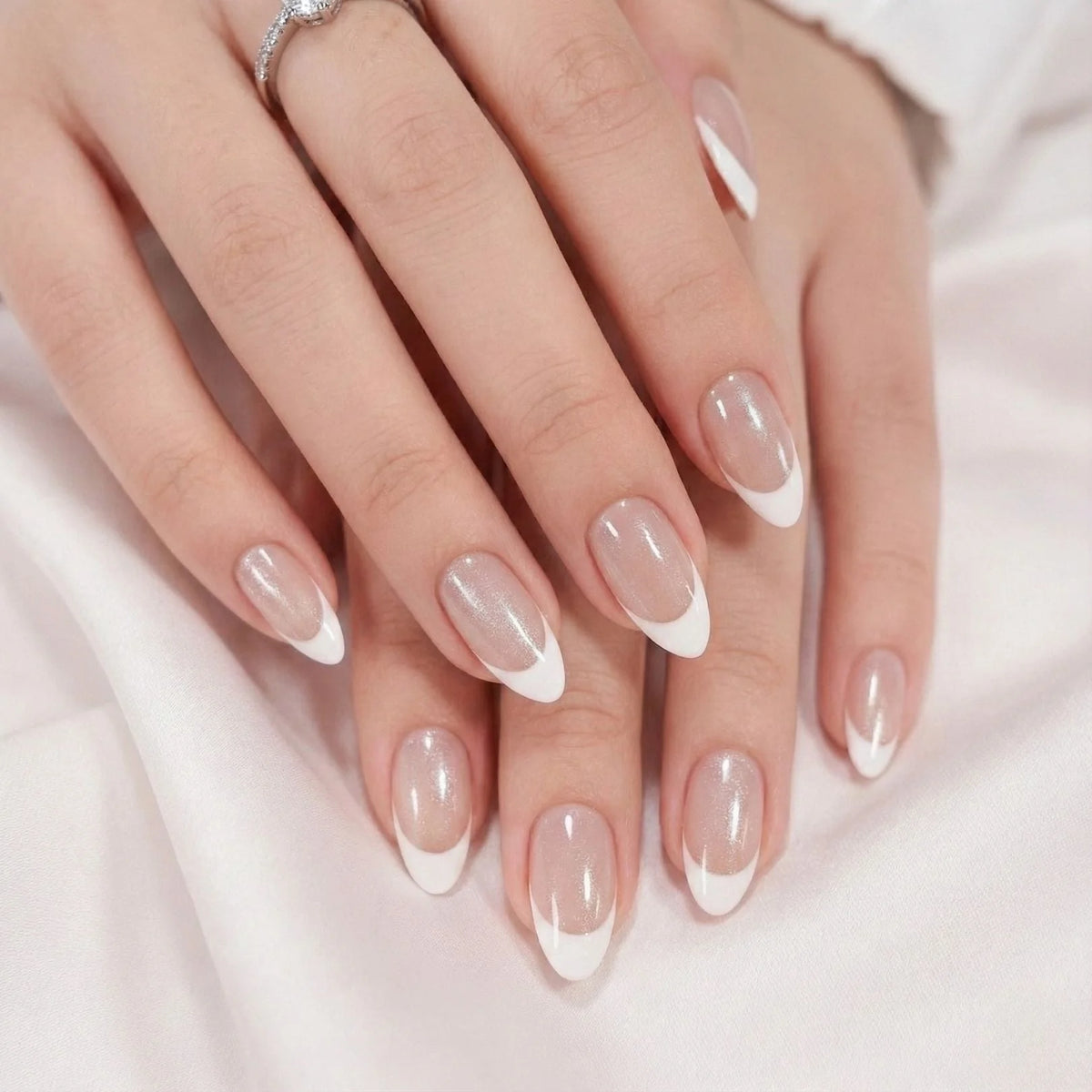 Faux ongles Sweet Sprinkle en scène – les deux mains, forme amande french nacrée sur tissu de soie blanc