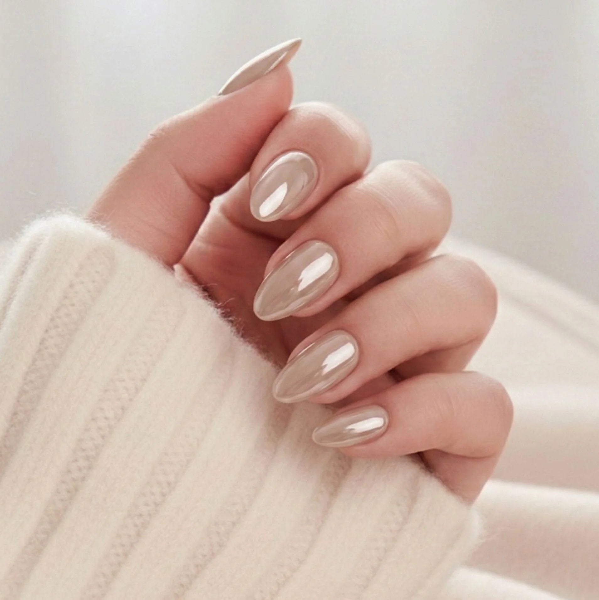 Pearly Perfection press-on naglar – mandelform i pearl taupe med metallic glans mot krämvit stickad tröja