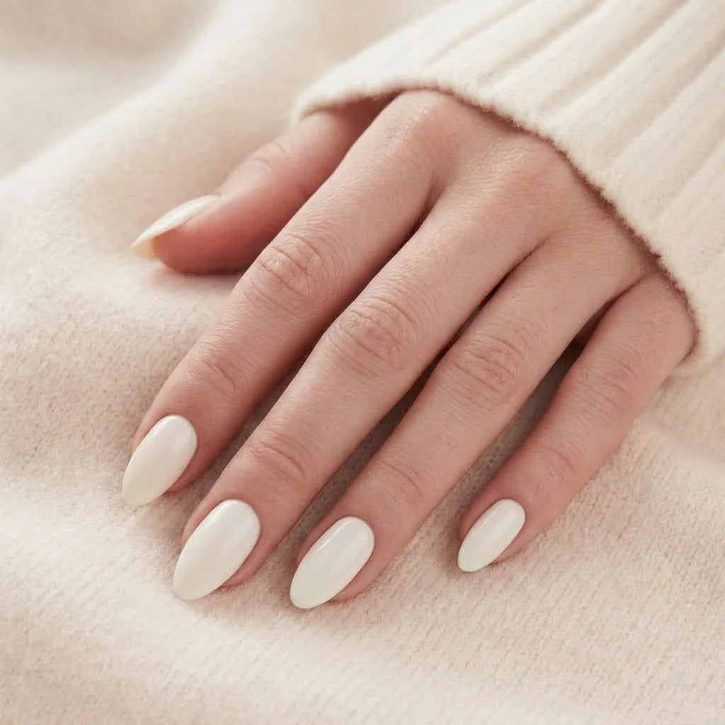 Satin Snow lösnaglar närbild – krämvita mandelnaglar mot beige cashmere-tröja