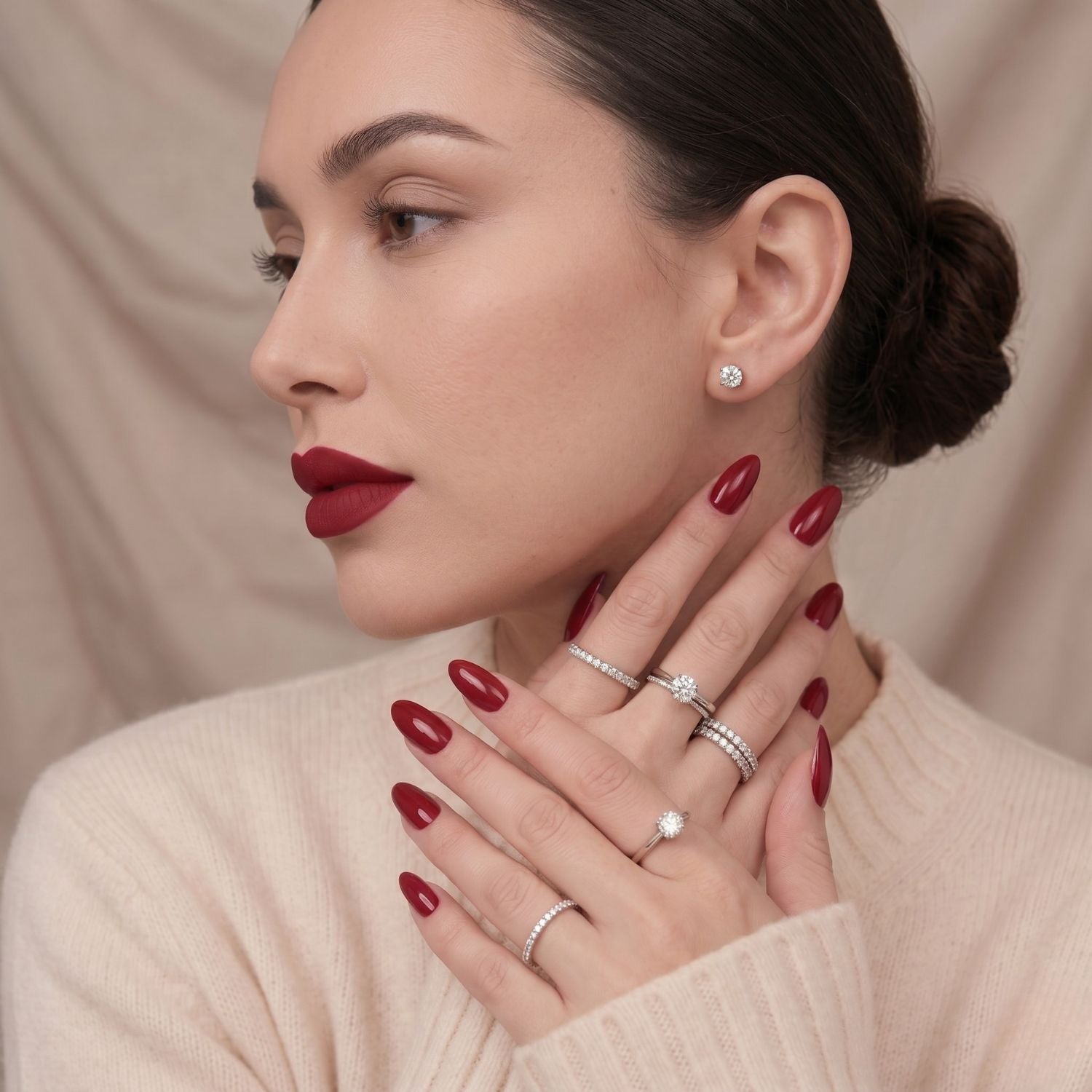 Ruby Romance vinröda press-on lösnaglar i mandelform. Elegant manikyr på modellens händer, matchande läppstift