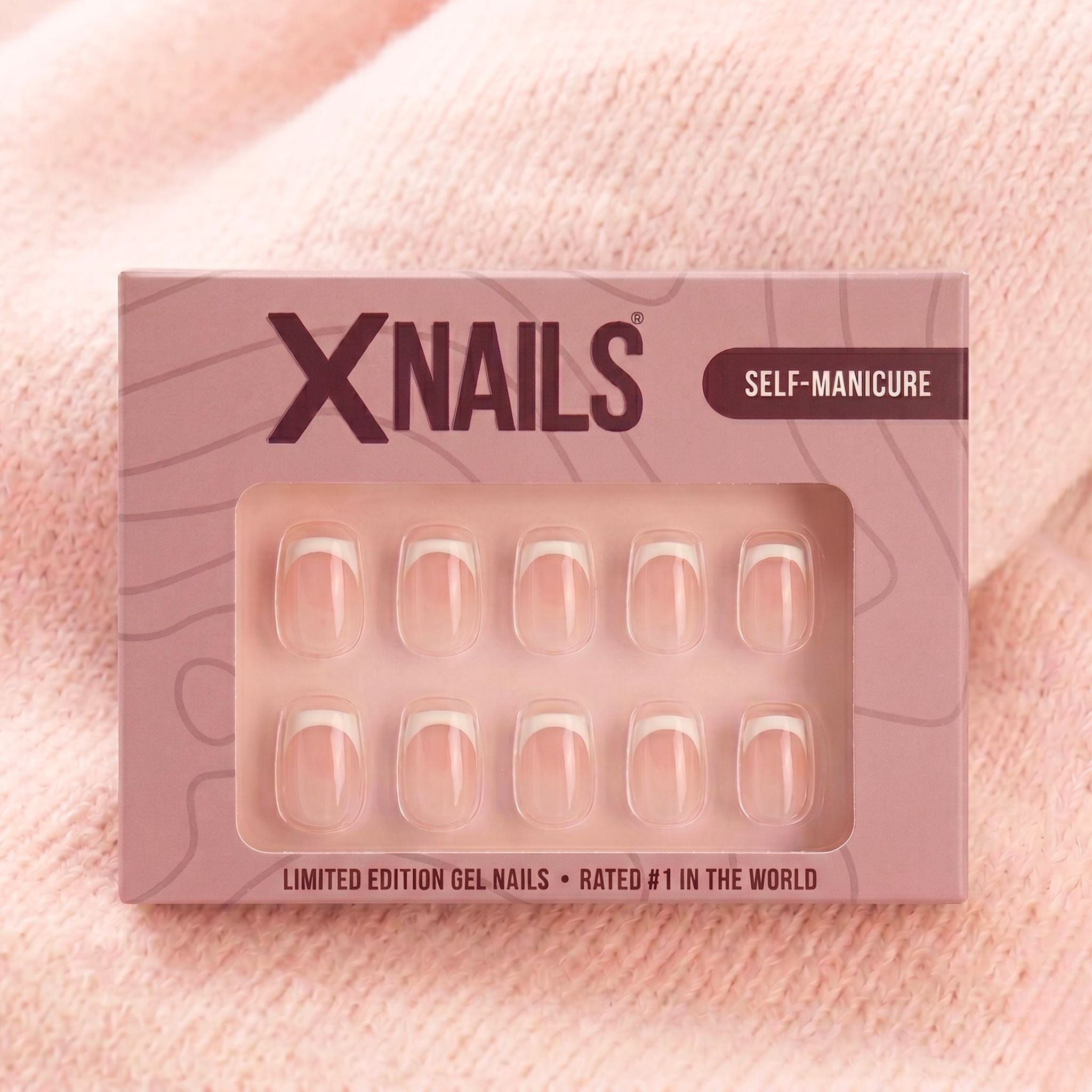XNails-förpackning med vita franska korta square press-on naglar mot rosa stickad bakgrund
