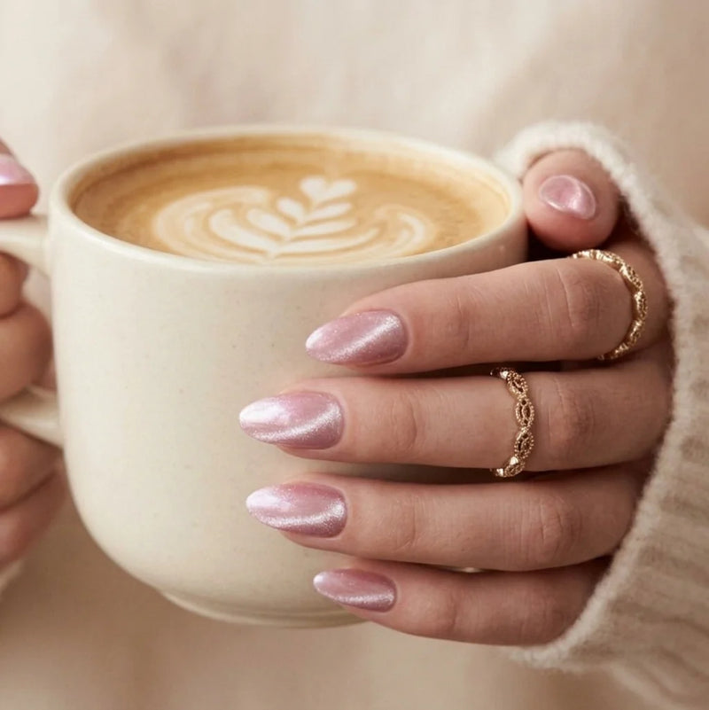 Faux ongles XNails sur une main qui tient un latte — ongles amande chrome rose