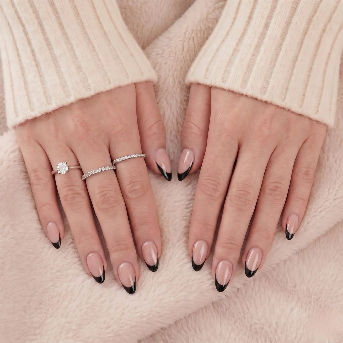 Faux ongles french almond noirs avec bagues argentées sur fourrure beige