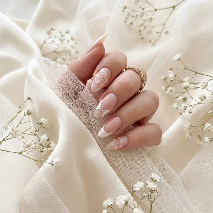 Main de la mariée avec les faux ongles press-on Bridal Bloom sur soie ivoire