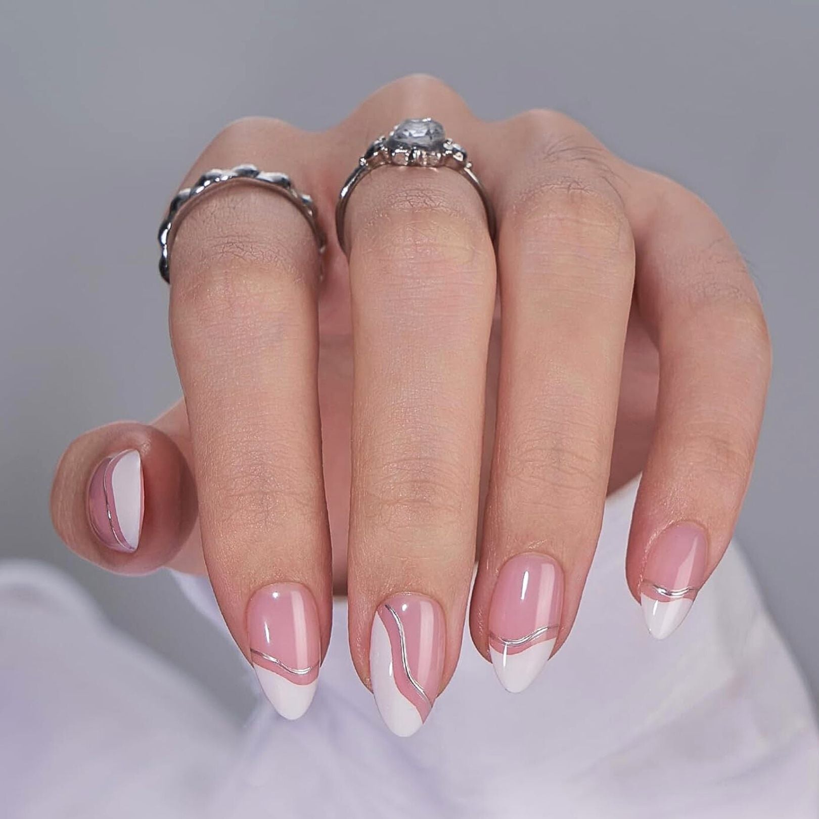 Nude beige press-on naglar – mandelform med naturlig glansig finish på hand med silverringar
