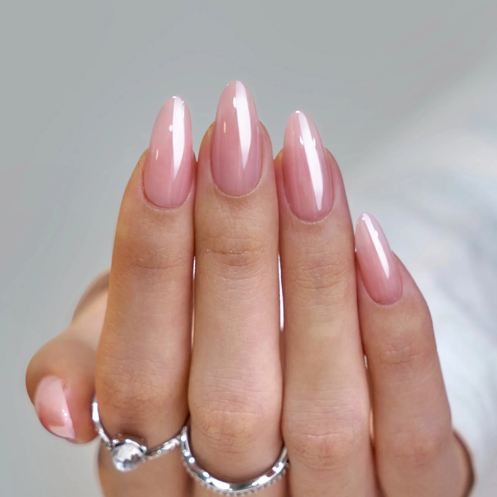 Pinkie Pearl naglar på hand – mjuk rosa pearl glans i mandelform närbild