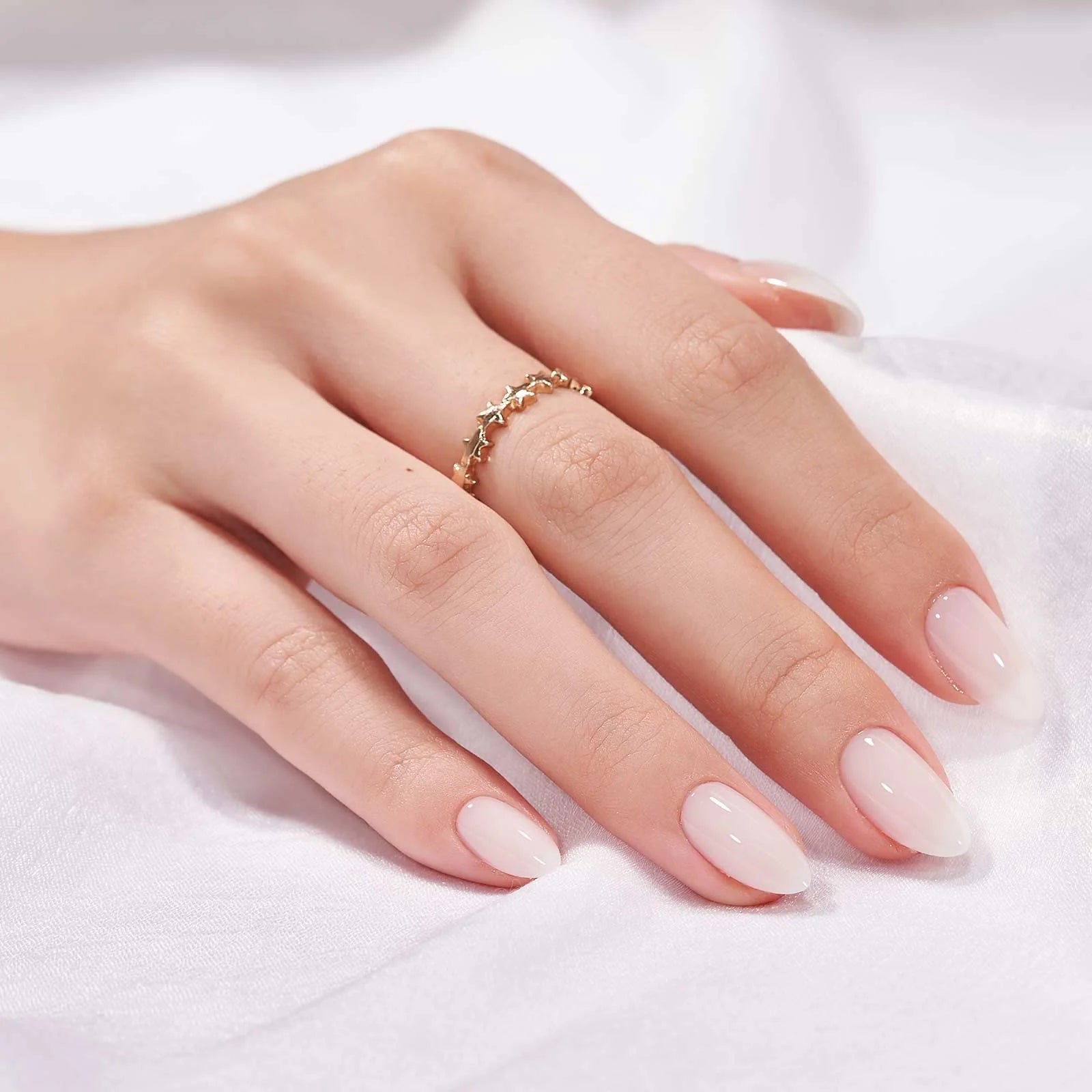 Satin Snow press-on naglar styling – nude mandelnaglar med guldring mot vit satin
