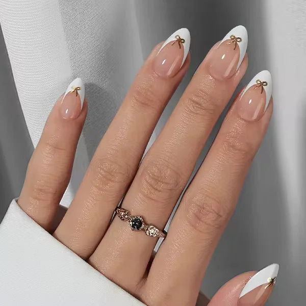 Blushing Bow mandelformade gelénaglar – fransk vit spets med guldrosettdetalj och silverring med hjärtsten