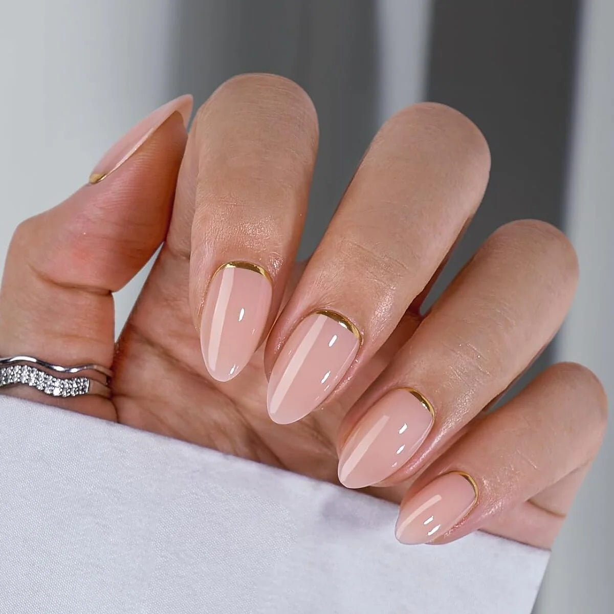 Golden Glimmer gelénaglar närbild – nude mandel med guld-detalj och silverring
