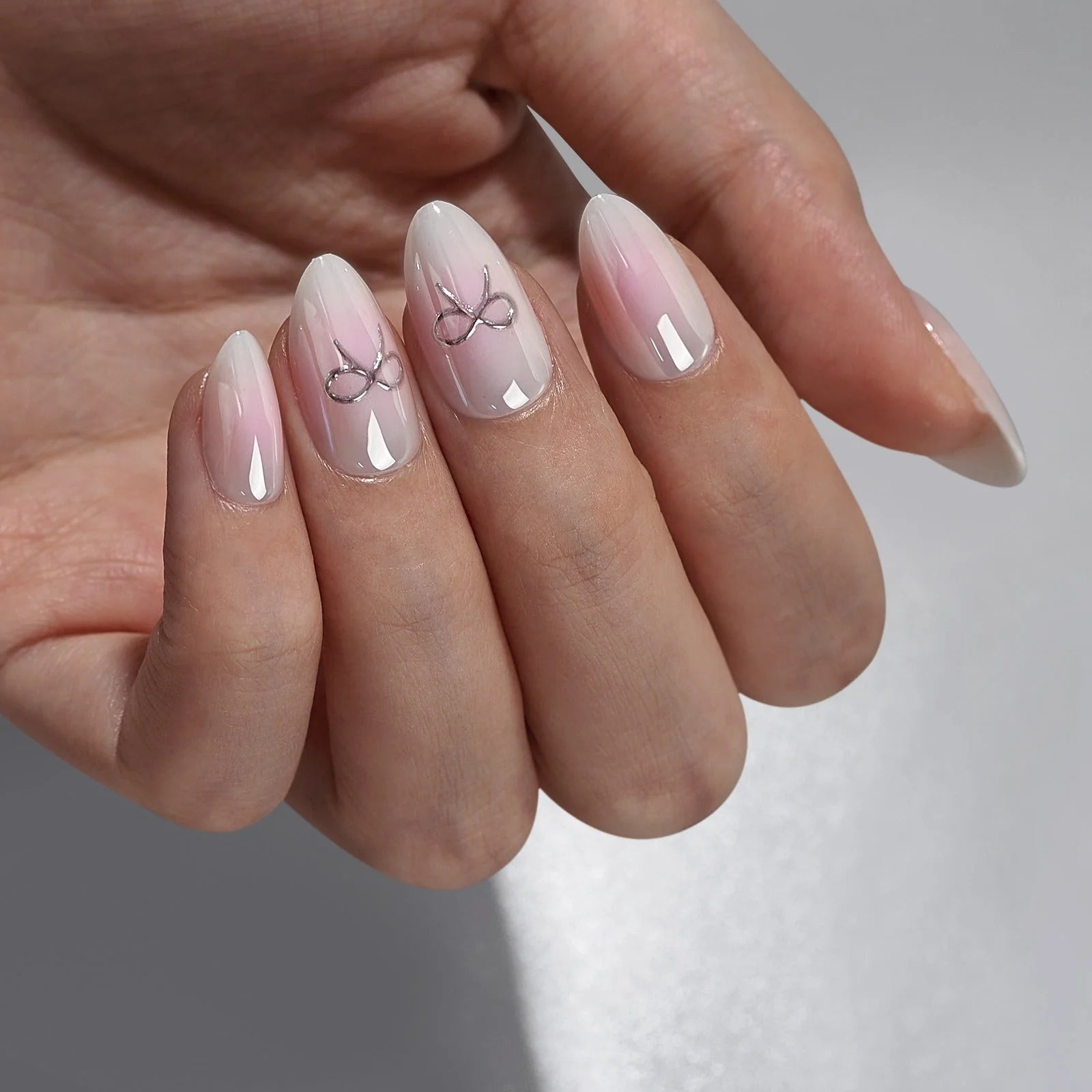 Aura Amoré mandelformade lösnaglar – mjuk rosa aura med silverrosett accentnaglar