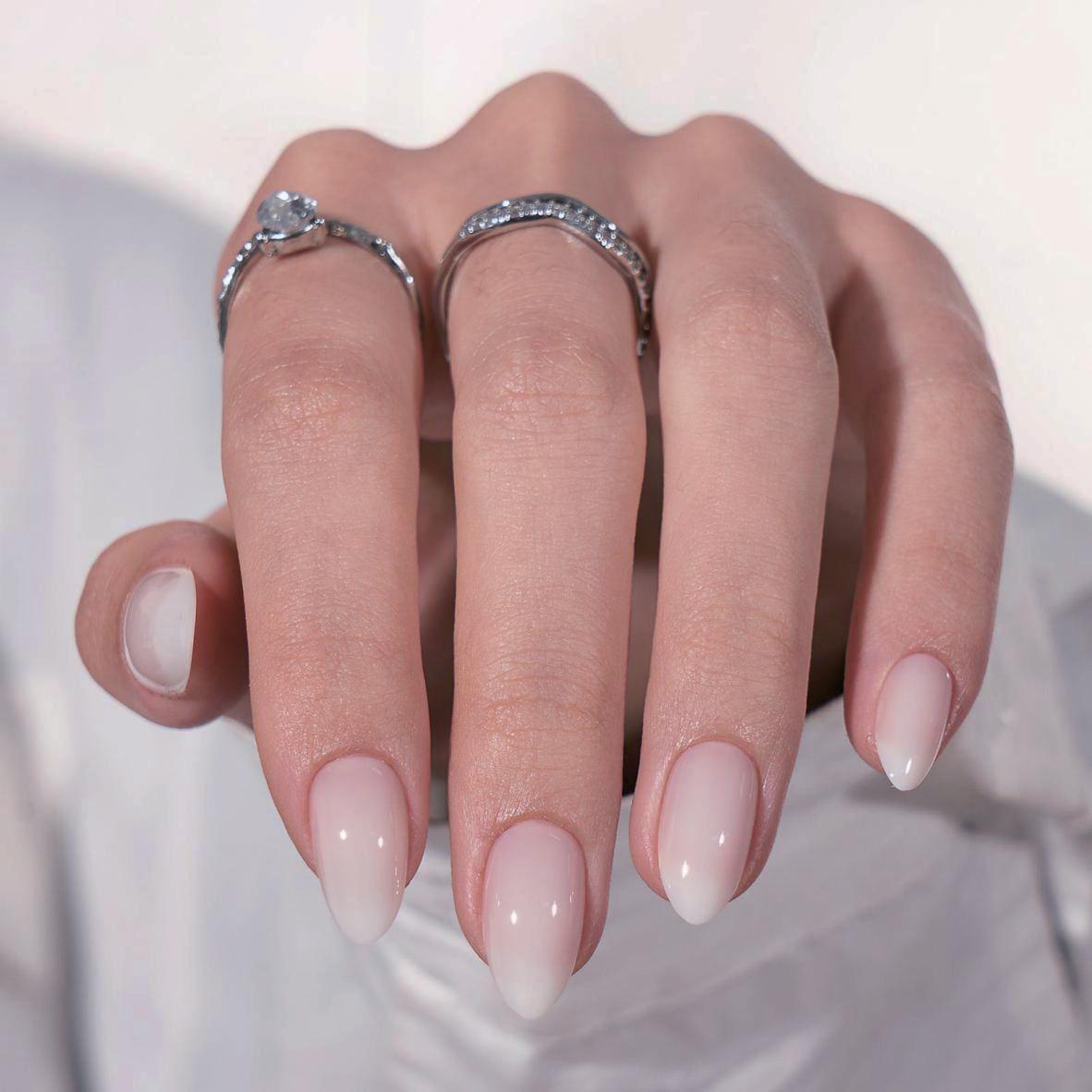 Nude press-on naglar – mandelform med glansig naturlig finish på hand med silverringar