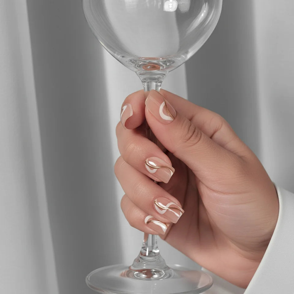 Summer Swirl press-on naglar styling – hand håller vinglas, korta square naglar med guld swirl
