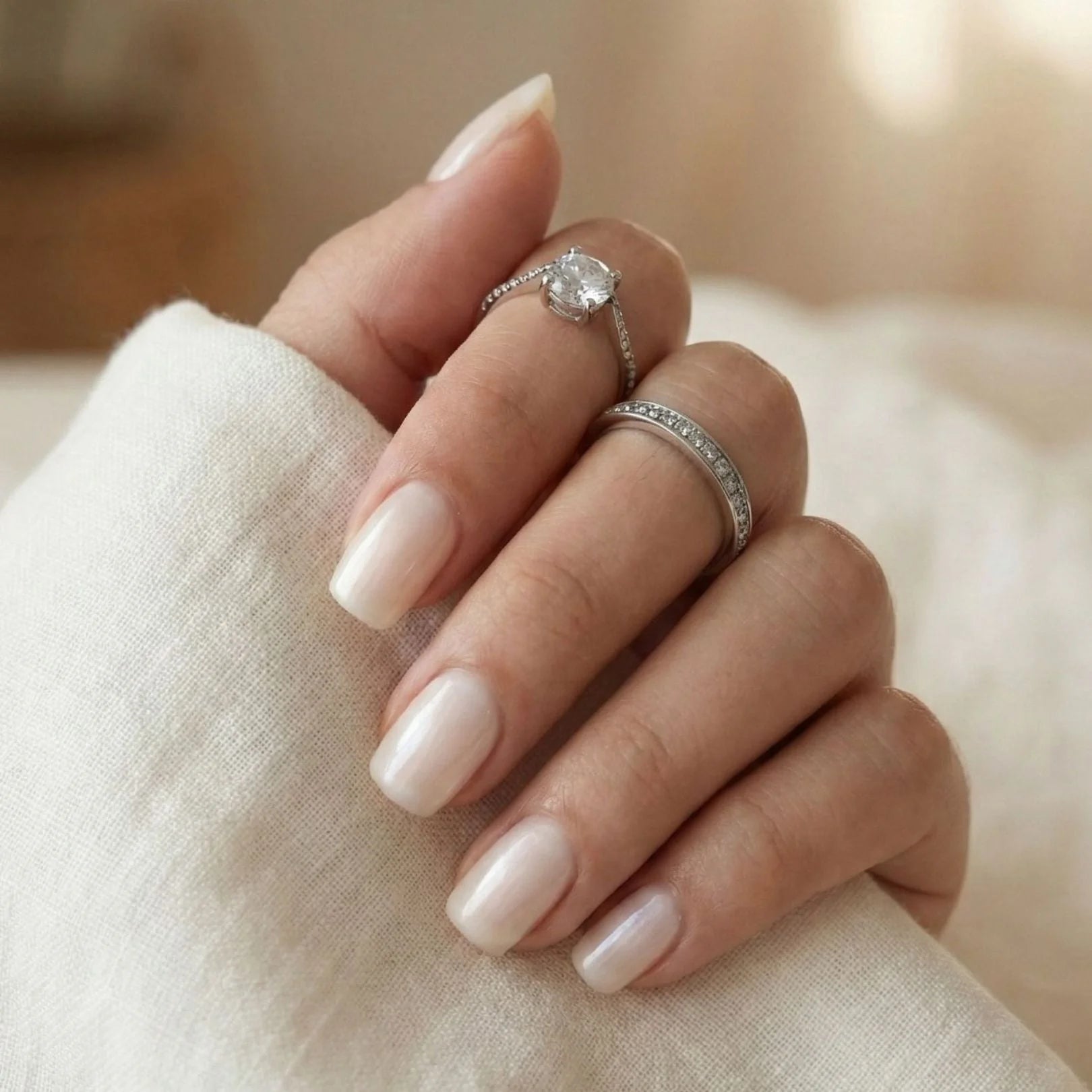 Pure Pearl gelénaglar närbild – kort square i pearl nude med vit blus och silverringar