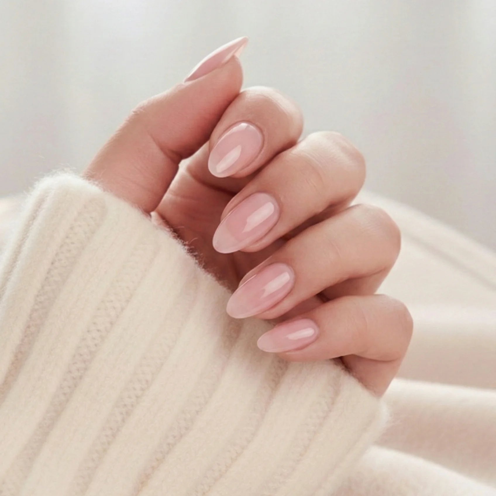 Pinkie Pearl press-on naglar – delikat rosa pearl i mandelform mot creme stickad tröja