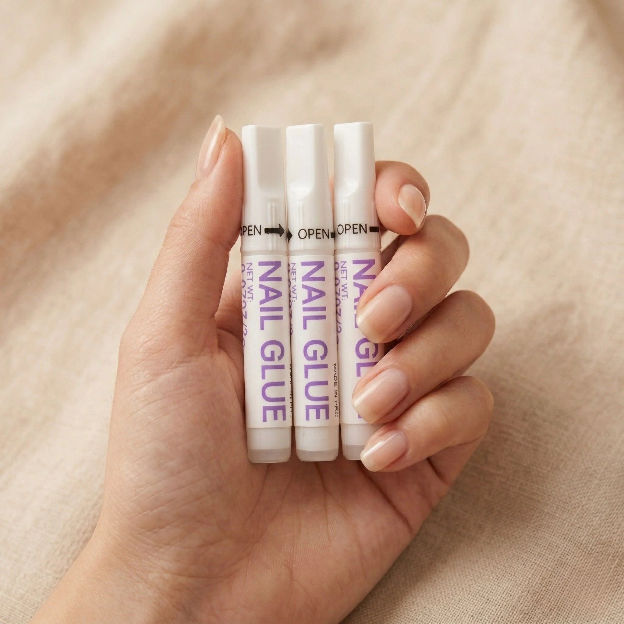 Colle à ongles XGlue en lot de 3 dans une main – colle forte pour faux ongles avec embout de précision