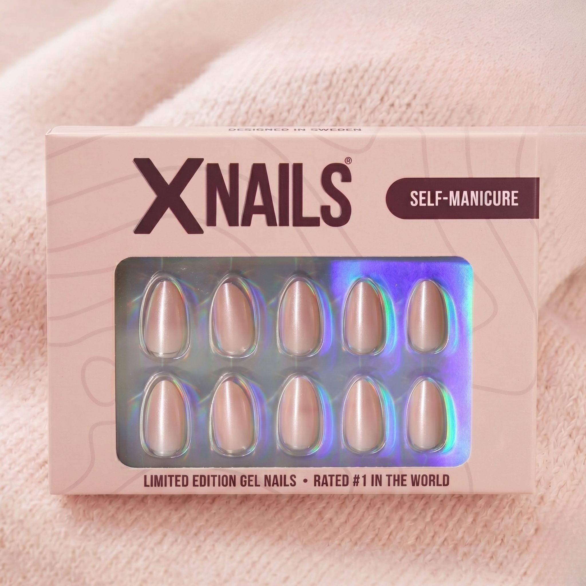 XNails-förpackning med silver chrome almond press-on naglar mot rosa stickad bakgrund