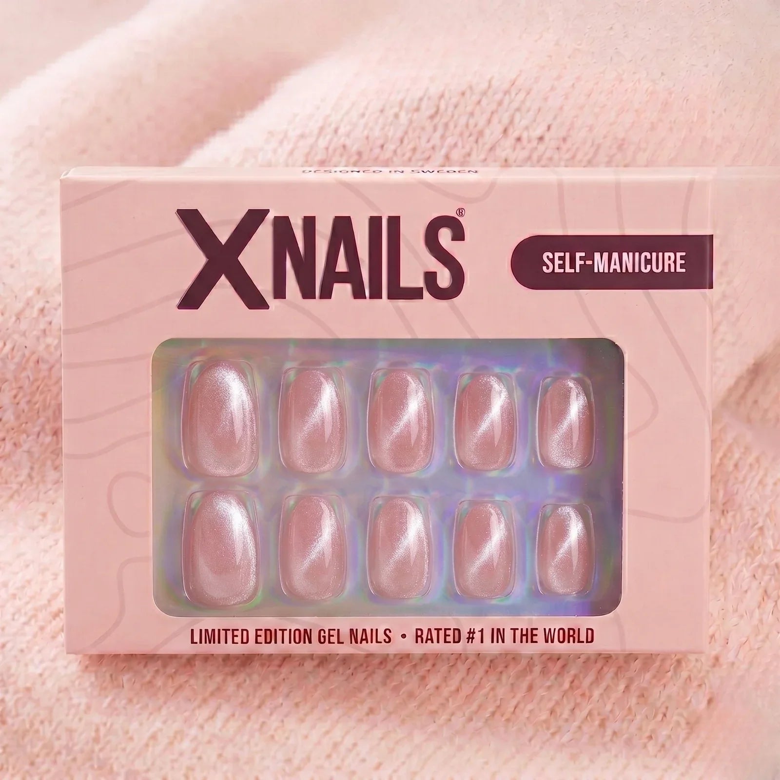 XNails-förpackning rosa chrome almond press-on naglar mot stickad rosa bakgrund