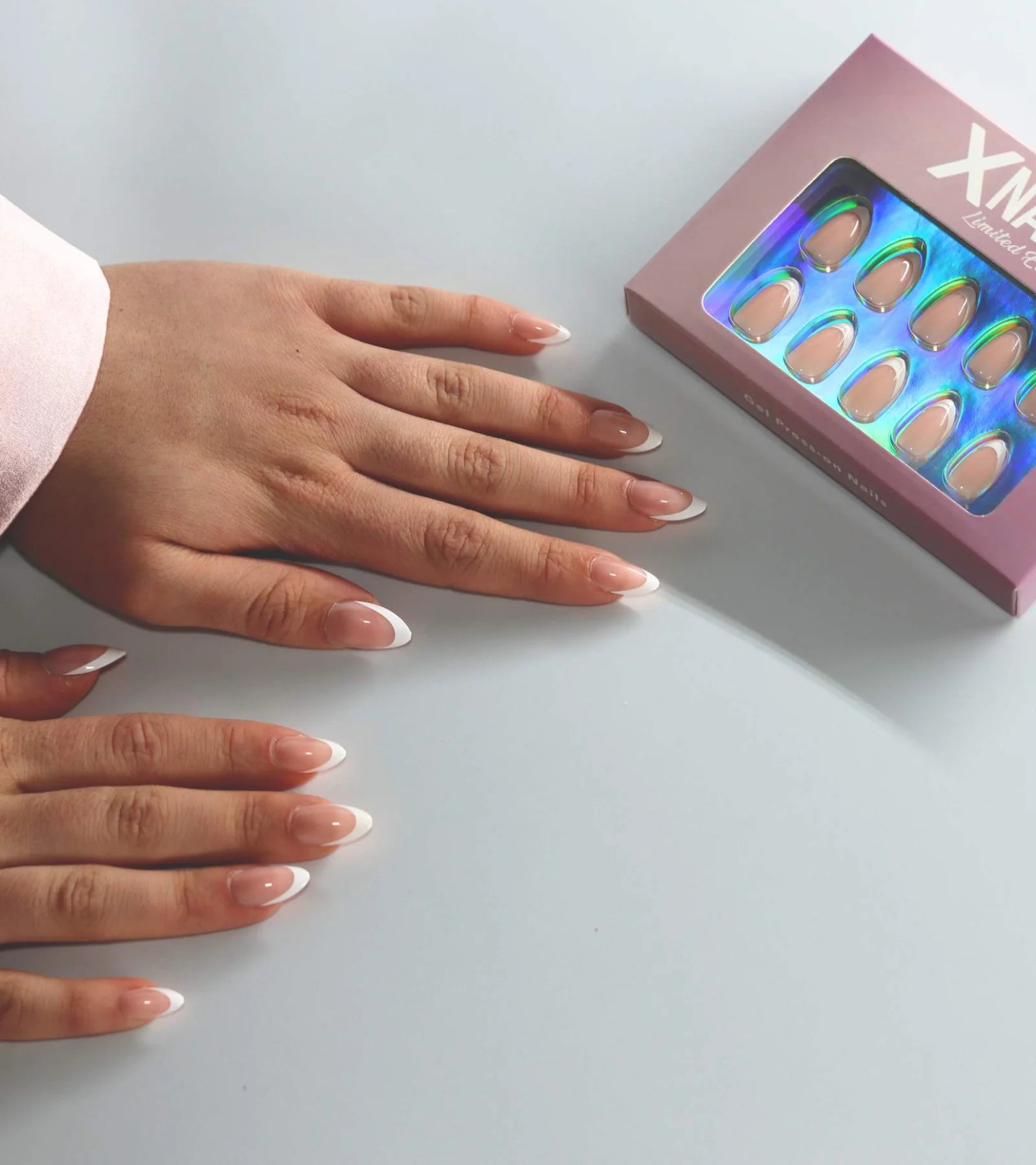 Två händer med franska press-on-naglar bredvid den beige XNails-asken